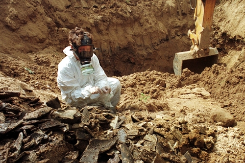 Eine Frau in Schutzkleidung untersucht eine illegale Müllkippe