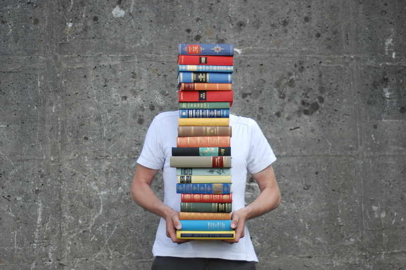 Titelbild Bildungsungleichheit, Mann hält Bücherstapel, sodass sein Gesicht nicht zu erkennen ist