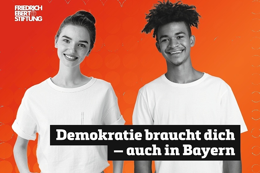 Zwei junge Personen mit freundlichen Gesichtern. In einem schwarzen Kasten steht in weißer Schrift: "Demokratie braucht dich - auch in Bayern".