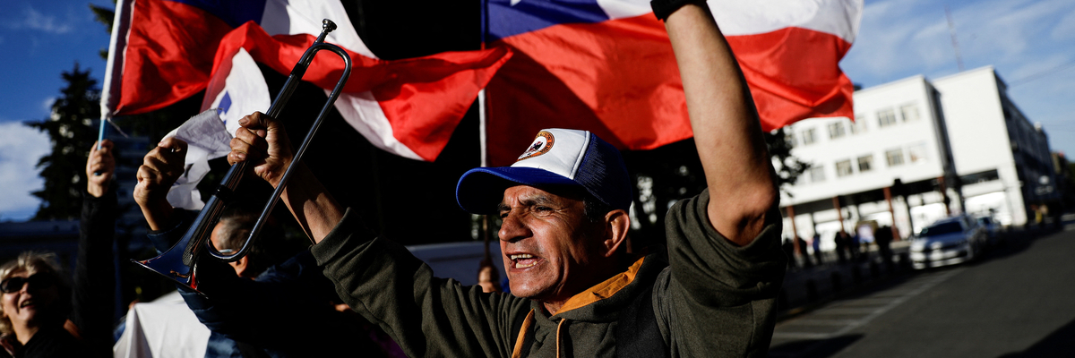 Demonstrant*Innen auf der Straße mit chilenischer Flagge im Hintergrund
