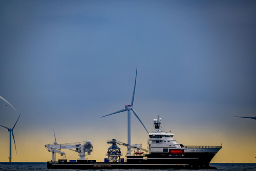 Ein Windpark auf dem Meer, im Vordergrund ein Schiff