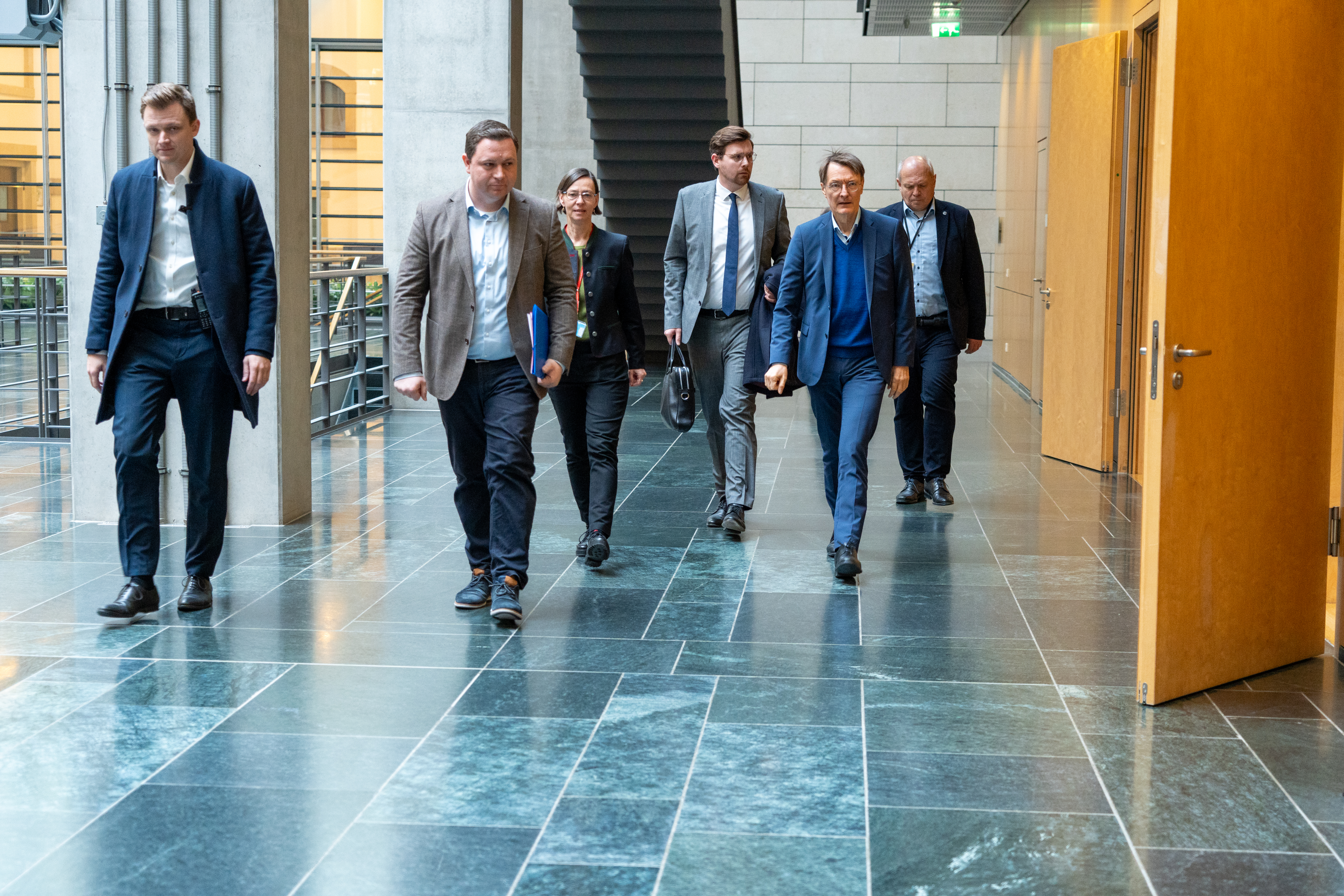 Prof. Dr. Karl Lauterbach ist in einem Gang des Bundestages unterwegs zu dem Raum mit den Teilnehmenden.