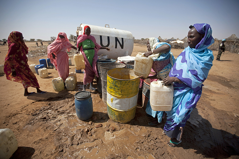 UN Wassercontainer für geflüchtete Menschen in Süd Darfur, von dem Frauen mit Kanistern Wasser schöpfen