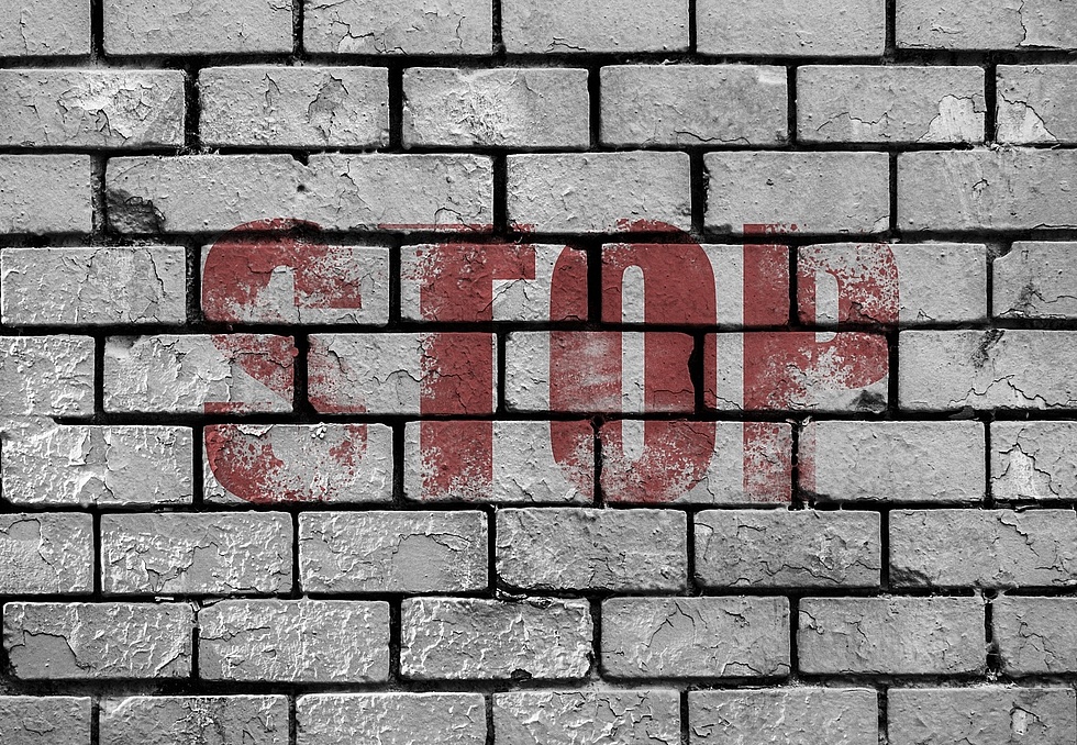 Graue Mauerwand und dem Schriftzug "STOP" gesprüht