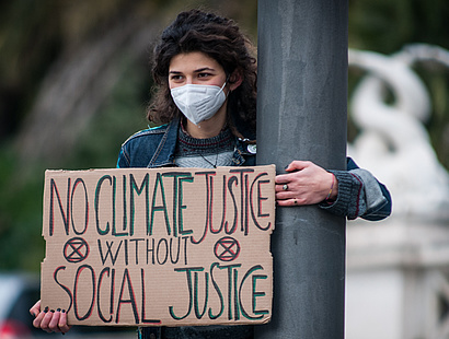 Mädchen mit Poster "No Climate Justice without Social Justice", zum Kompetenzzentrum sozialökologische Transformation