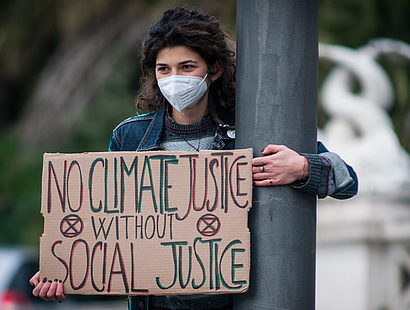 Mädchen mit Poster "No Climate Justice without Social Justice", zum Kompetenzzentrum sozialökologische Transformation
