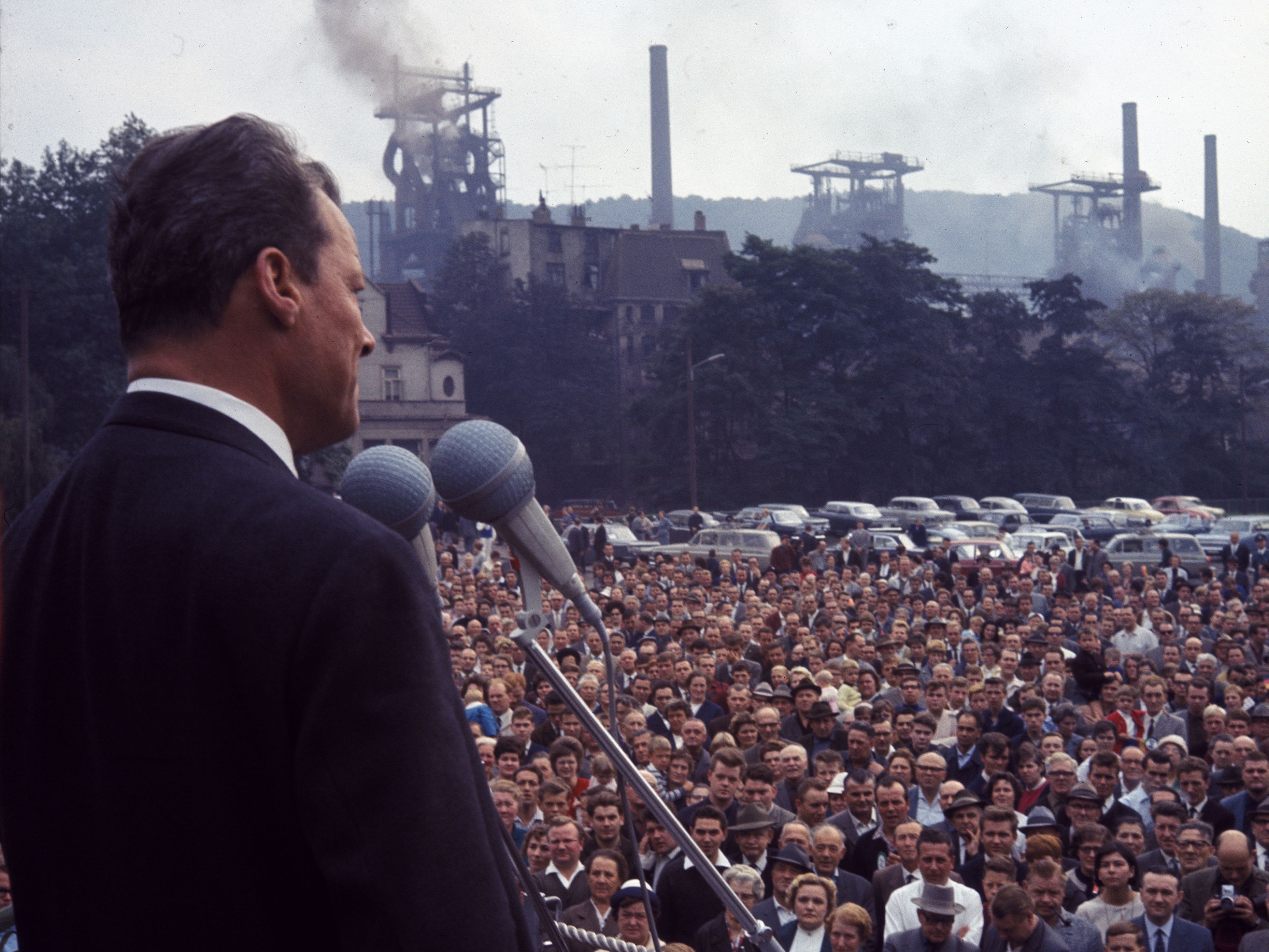 Willy Brandt steht 1965 für seinen Wahlkampf auf einer Bühne. Vor Ihm eine steht eine Menschenmenge.