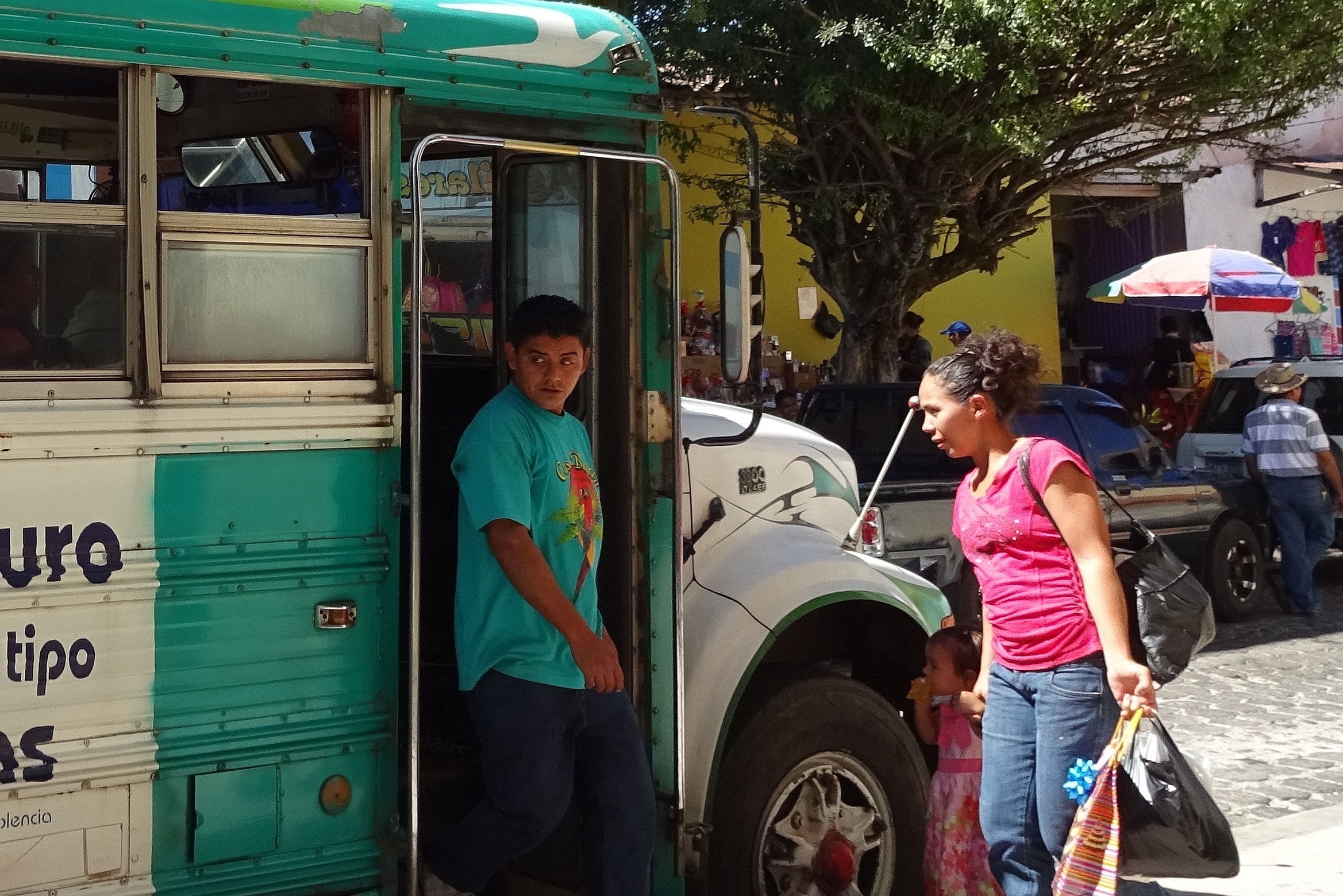 Menschen beim Ein- und Aussteigen in den/aus dem Bus in El Salvador