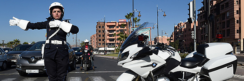 Polizistin in Marokko steht neben ihrem Motorrad auf der Straße und leitet den Verkehr.