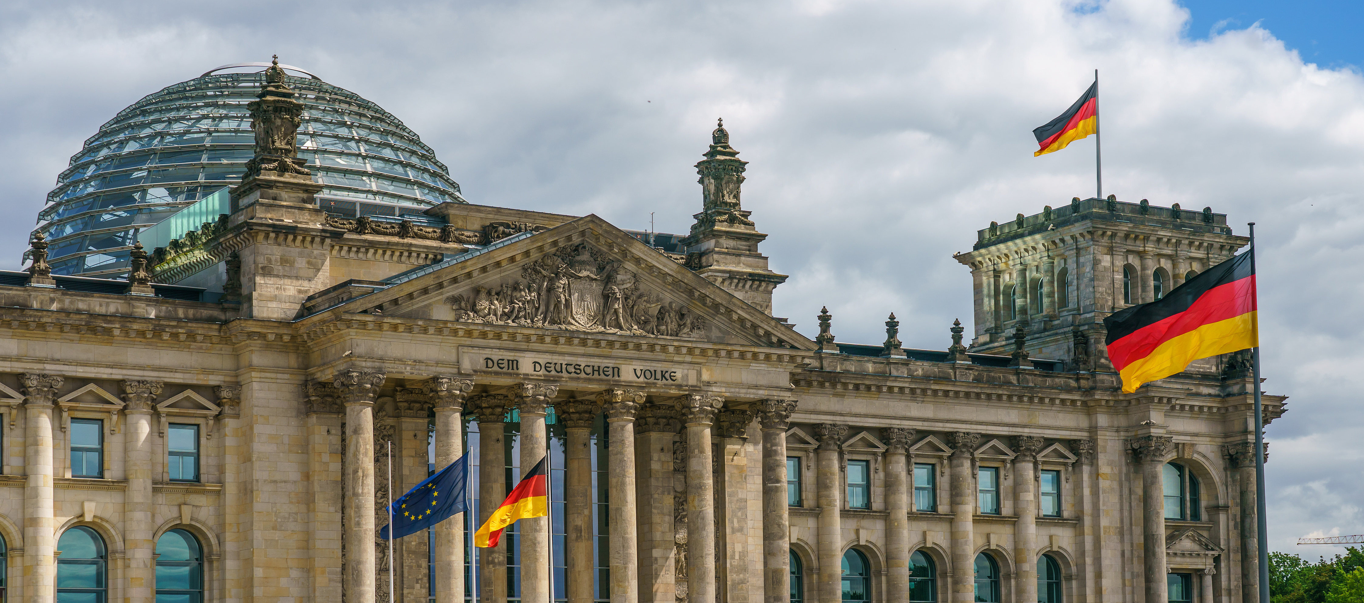 Foto von der Außenansicht des Bundestag, Haupteingang, mit wehenden Flaggen.