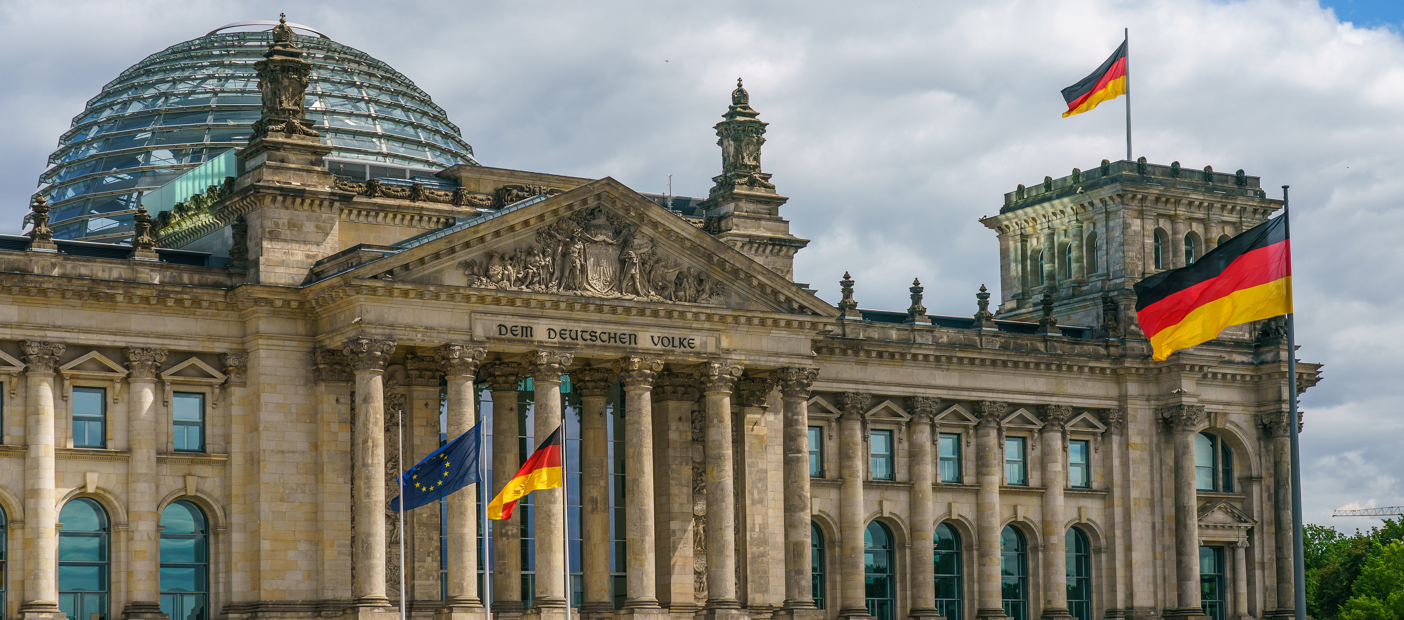 Foto von der Außenansicht des Bundestag, Haupteingang, mit wehenden Flaggen.