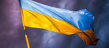 Flagge der Ukraine weht vor dunklem Himmel