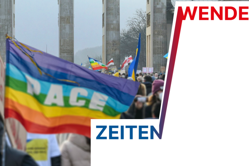 Eine Traube an Menschen demonstrieren vor dem Brandenburger Tor. In der Mitte des Bildes steht ein Demonstrant mit einer Pace-Fahne. Der Schrifzug "Zeiten - Wende" ist als Grafik zu lesen.