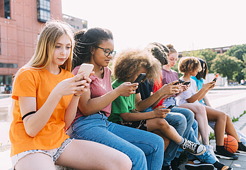 Jugendliche surfen an einem sonnigen Tag mit ihrem Smartphone im Internet.