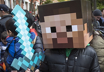 Junger Mensch mit Minecraft Pappschwert und Pappkopf beteiligt sich an einer Demonstration.