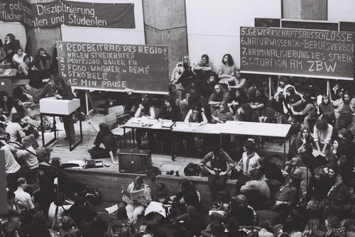 Schwarz-Weiß-Fotografie einer Veranstaltung im Audimax der Technischen Universität Berlin (TU) am 11.01.1977 anlässlich des bundesweiten Streiks der Universitäten und Fachhochschulen 1976/77 in Westdeutschland und Berlin