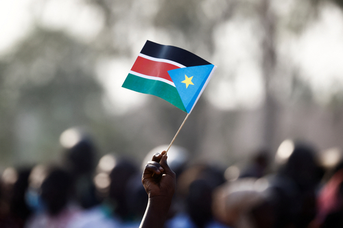 A hand waving a South Sudanese flag
