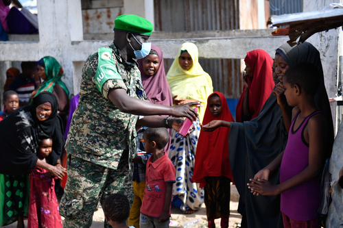 Soldat mit Coronaschutzmaske desinfiziert einem Mädchen die Hand in Mogadishu.