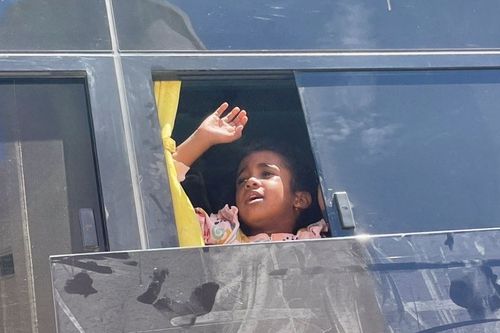 Winkendes Mädchen im Bus bei der Evakuierung im Sudan
