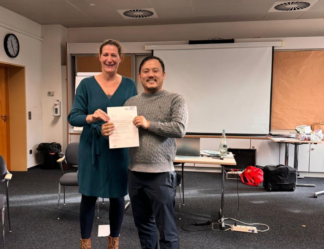 Jingmin Zhang erhält sein Zertifikat von Anne Haller