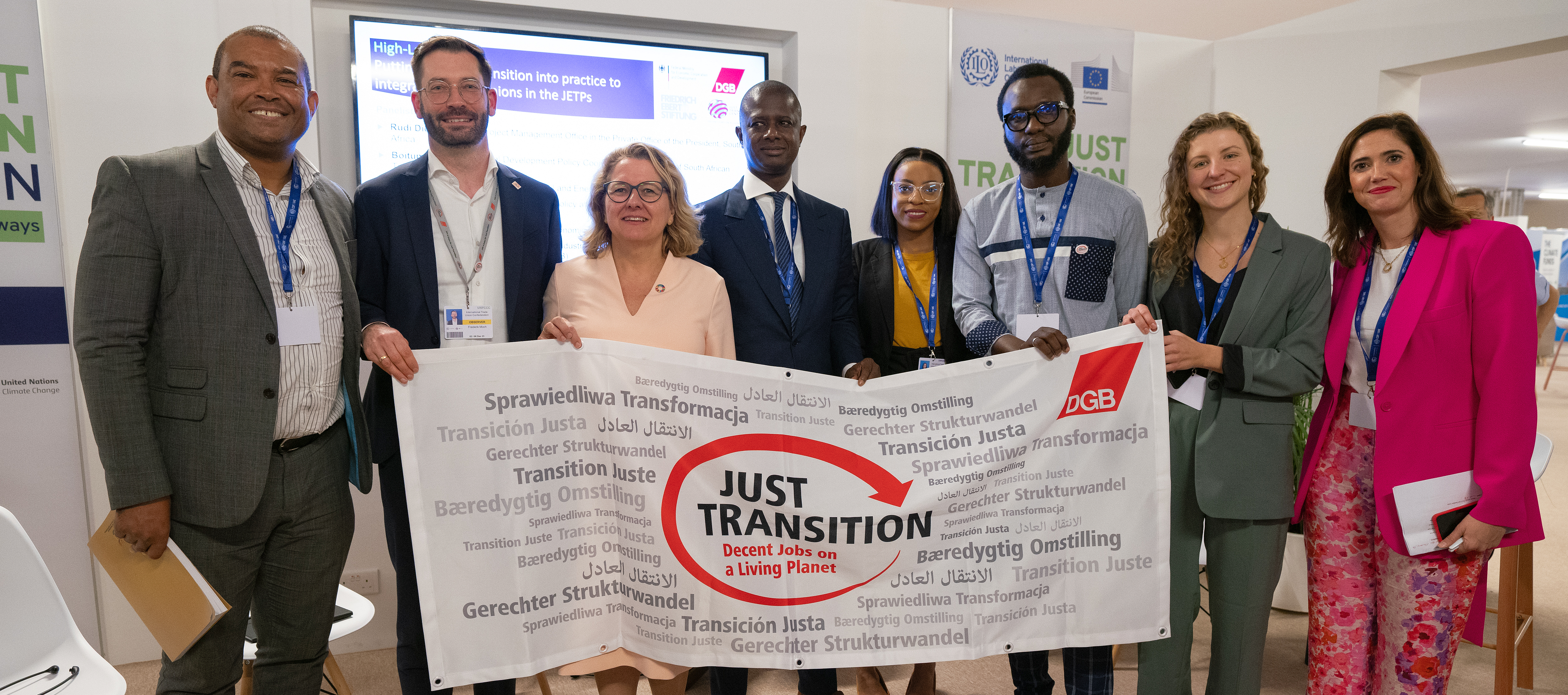 Speakers of the FES-DGB side event in the ILO pavilion at COP28 with Development Minister Svenja Schulze. The group holds a poster with the words Just Transition.