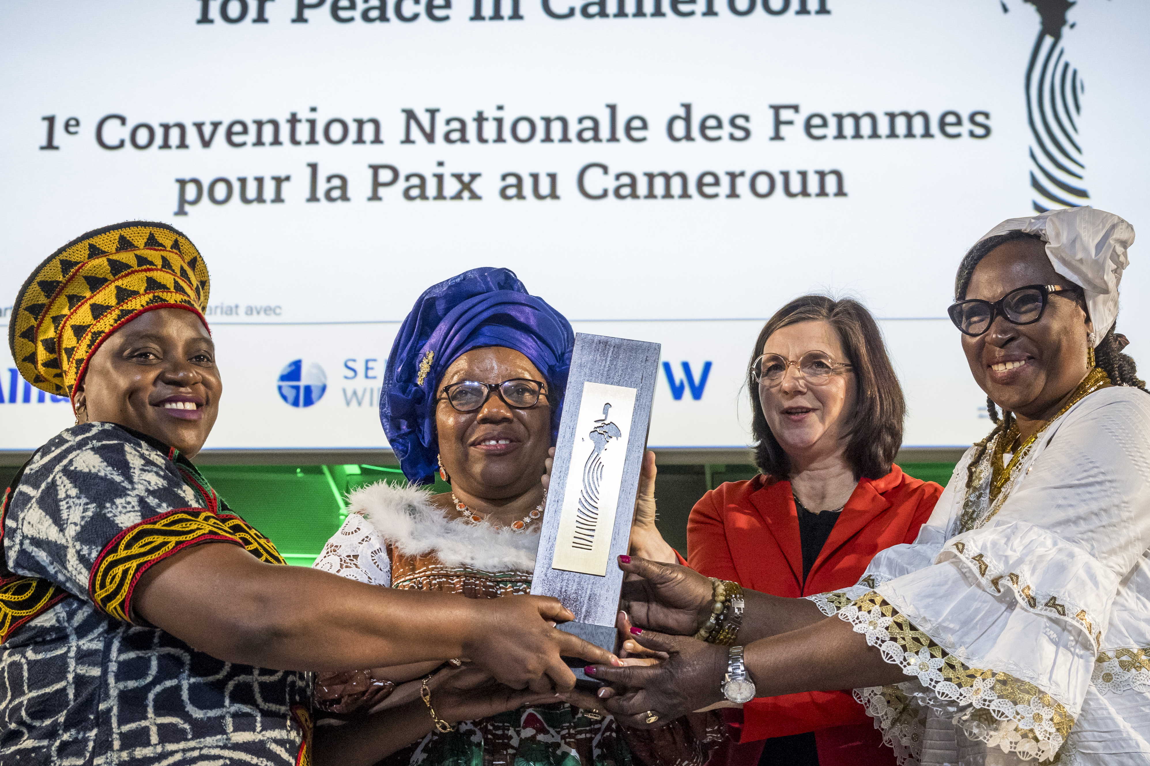 Sally Mboumien, Marthe Wandou, Esther Omam nehmen stellvertretend für die Frauenfriedensplattform Kamerun den Deutschen Afrika-Preis 2023 entgegen und halten die Skulptur hoch.