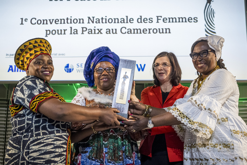 Sally Mboumien, Marthe Wandou, Esther Omam nehmen stellvertretend für die Frauenfriedensplattform Kamerun den Deutschen Afrika-Preis 2023 entgegen und halten die Skulptur hoch.