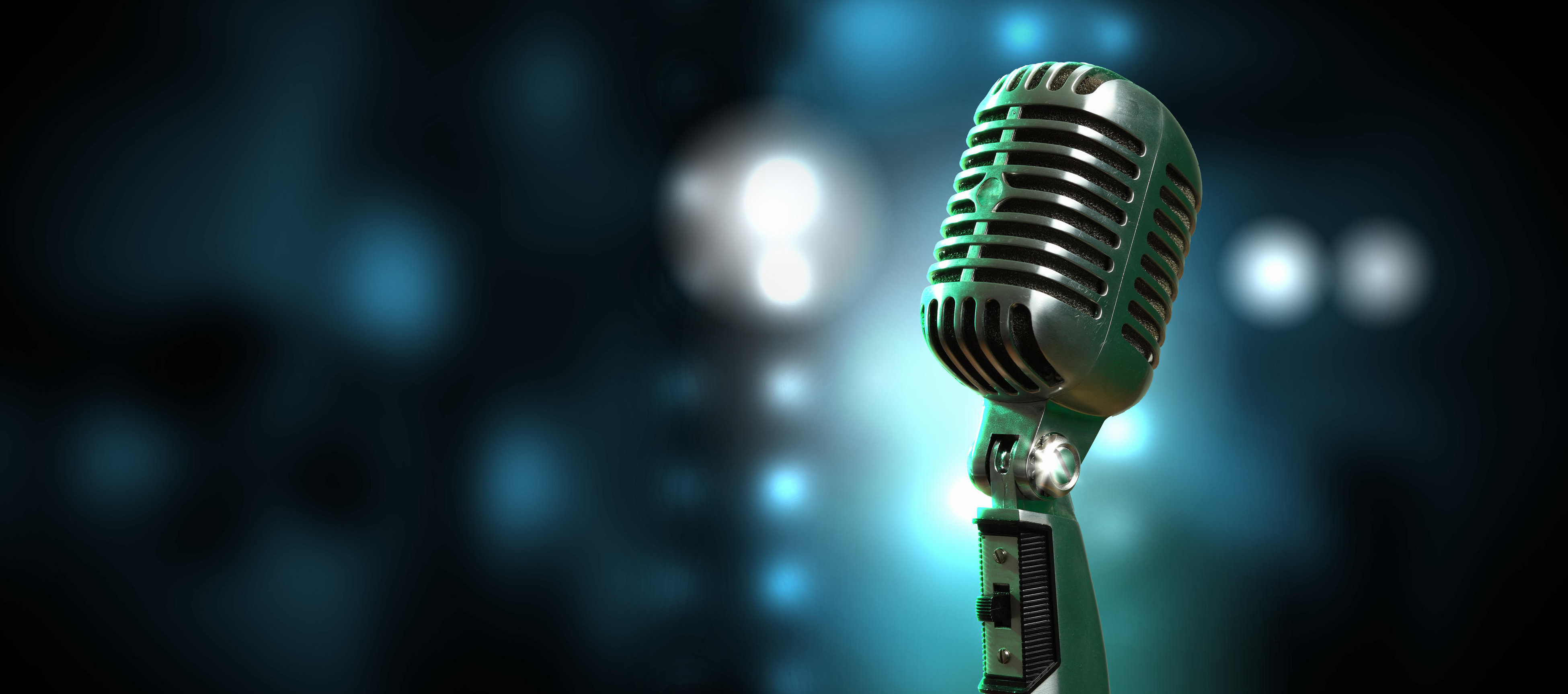 Ein Mikrofon auf der Bühne mit hellblauen Lichtern im Dunklen.