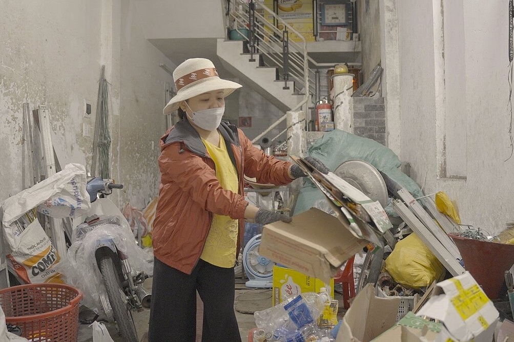 Truong Thi Phi Yen, eine informelle Müllarbeiterin, bei der täglichen Arbeit in einer Gasse beim Mülltrennen