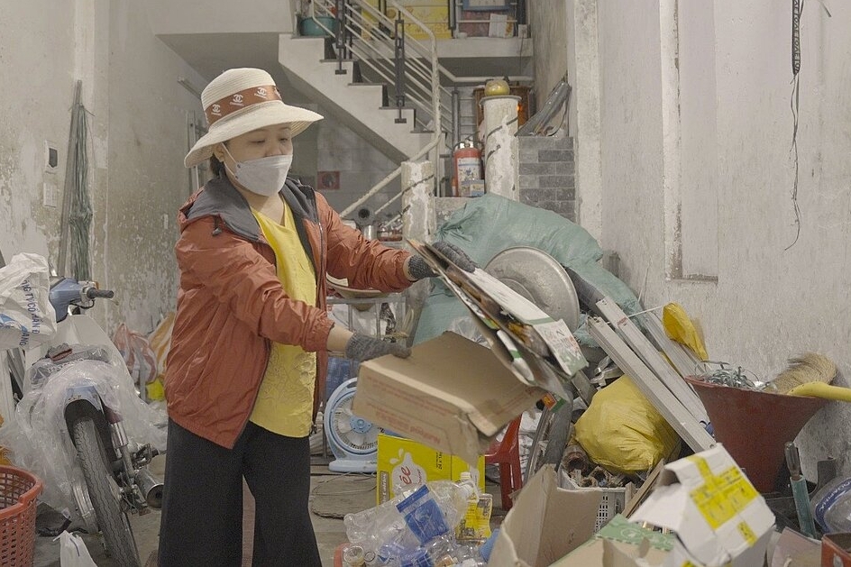 Truong Thi Phi Yen, eine informelle Müllarbeiterin, bei der täglichen Arbeit in einer Gasse beim Mülltrennen