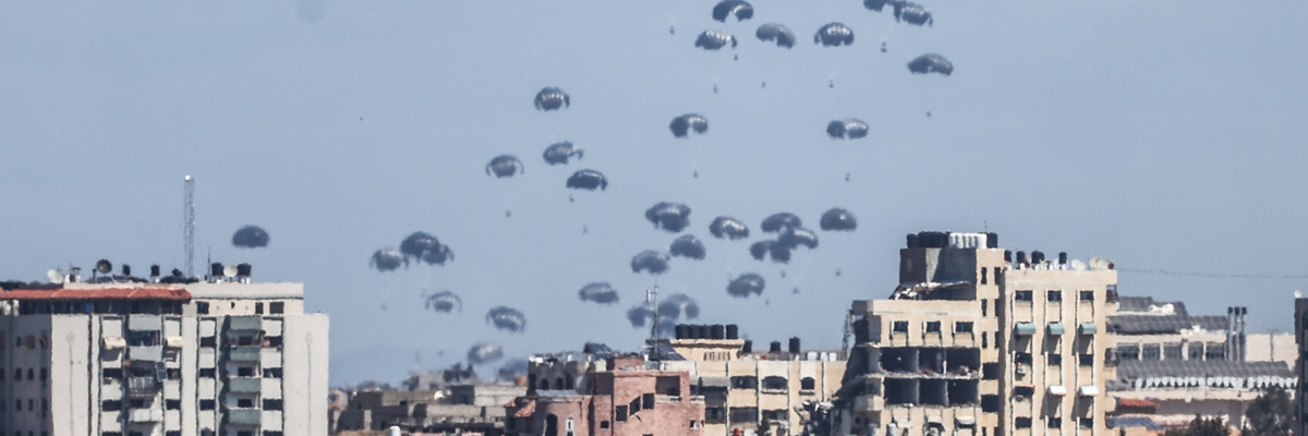 Viele Fallschirme mit Hilfsgütern am Himmel über einer Stadt in Gaza.