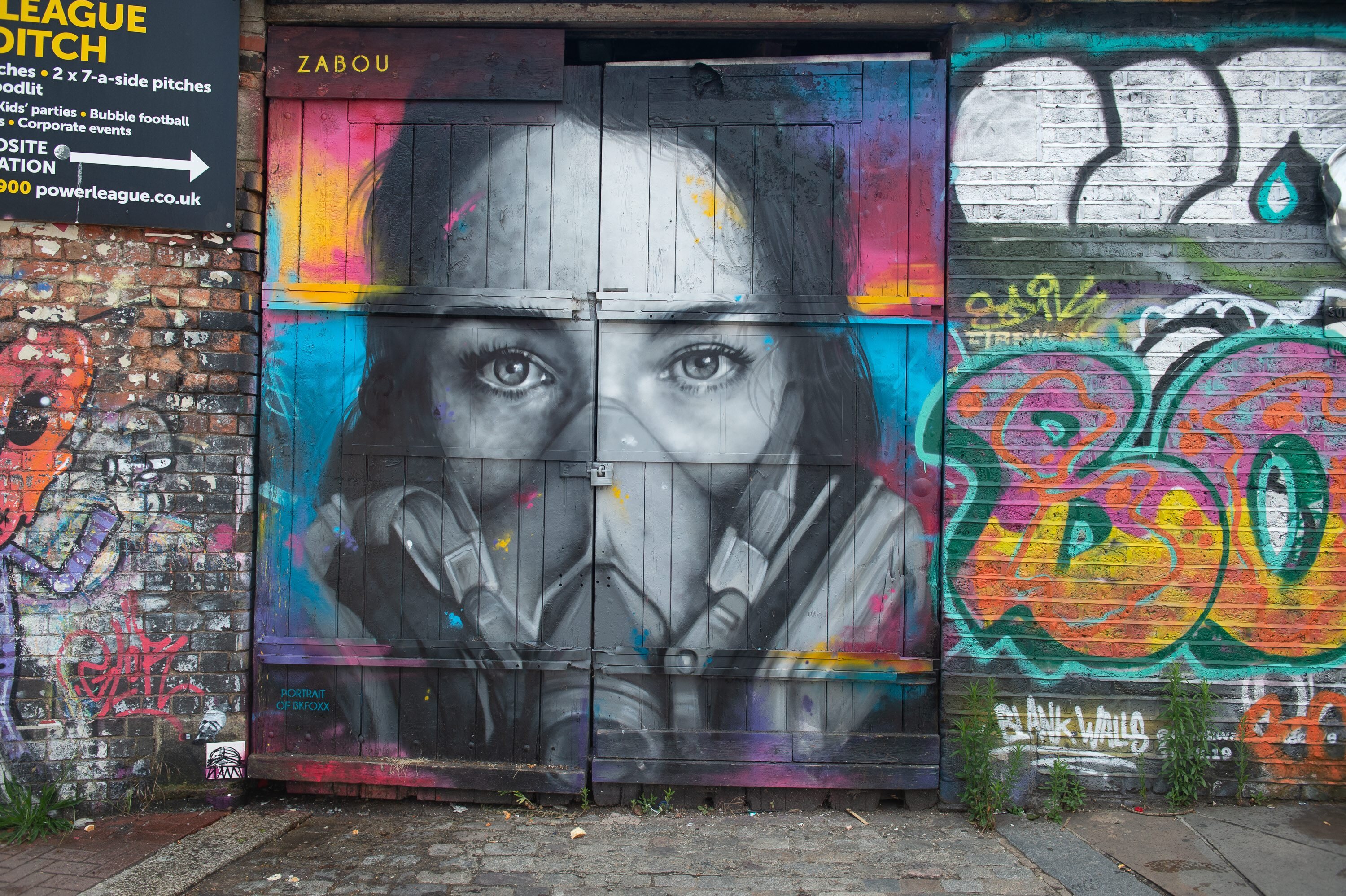 Das Graffiti des Straßenkünstlers Zabou zeigt eine junge Frau mit Maske.