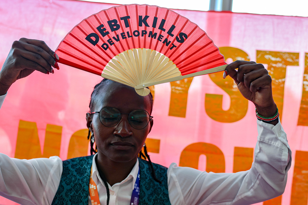 Eine Aktivistin hält einen Fächer mit der Aufschrift "Debt Kills Development" (Schulden töten Entwicklung) während eines Protestes auf dem FfD4-Gipfel der UN hoch.t.