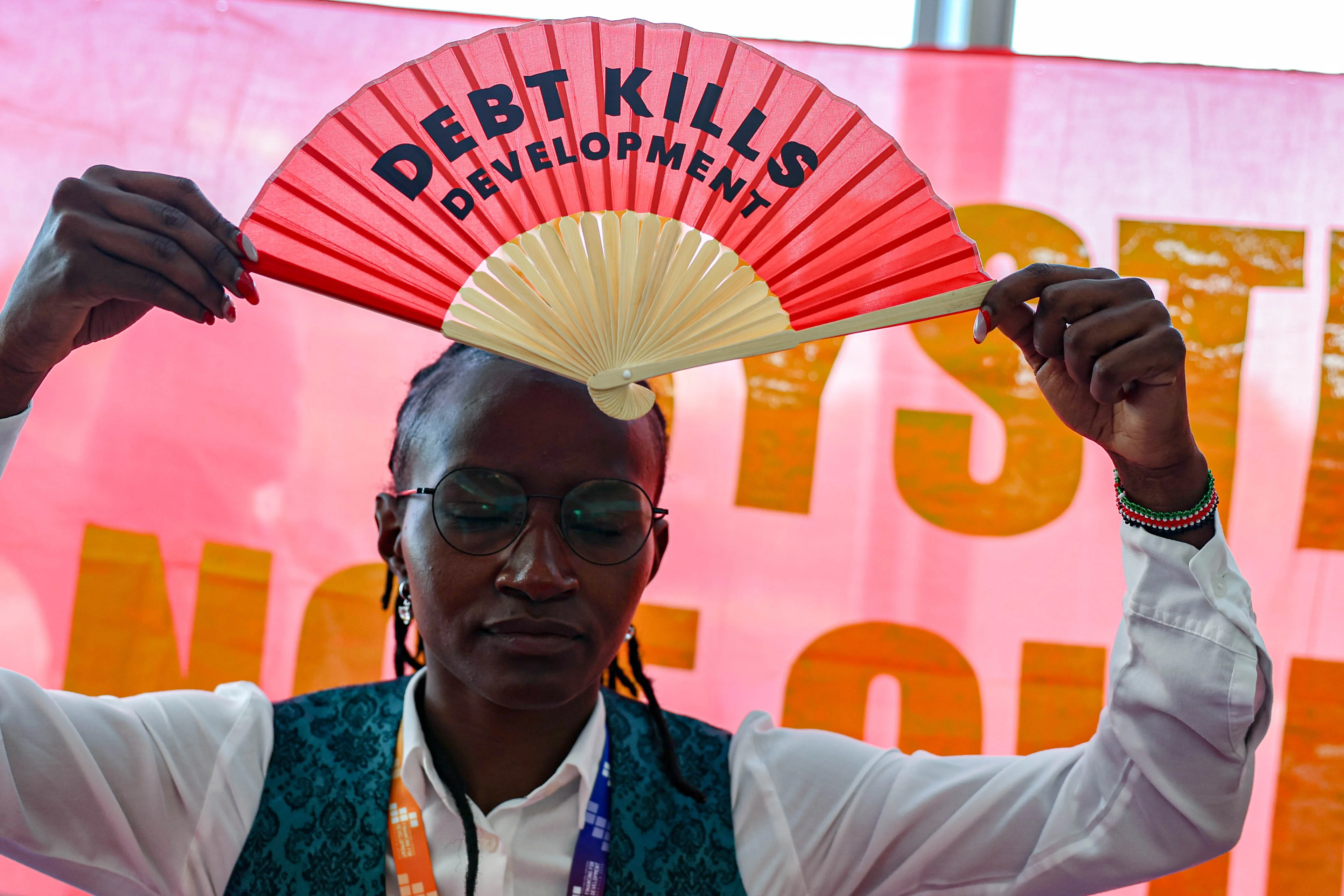 Eine Aktivistin hält einen Fächer mit der Aufschrift "Debt Kills Development" (Schulden töten Entwicklung) während eines Protestes auf dem FfD4-Gipfel der UN hoch.t.