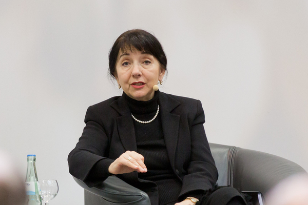 Petra Rosenberg sitzend auf der Tibüne berichtet dem Publikum.