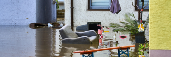 Möbel schwimmen im Hochwasser vor einem Haus