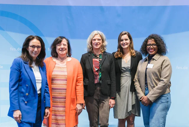 Group photo in front of a blue backdrop featuring Yasmin Fahimi, Dr Bärbel Kofler, Dr Sabine Fandrych, Kelly Fay Rodríguez and Zingiswa Losi.