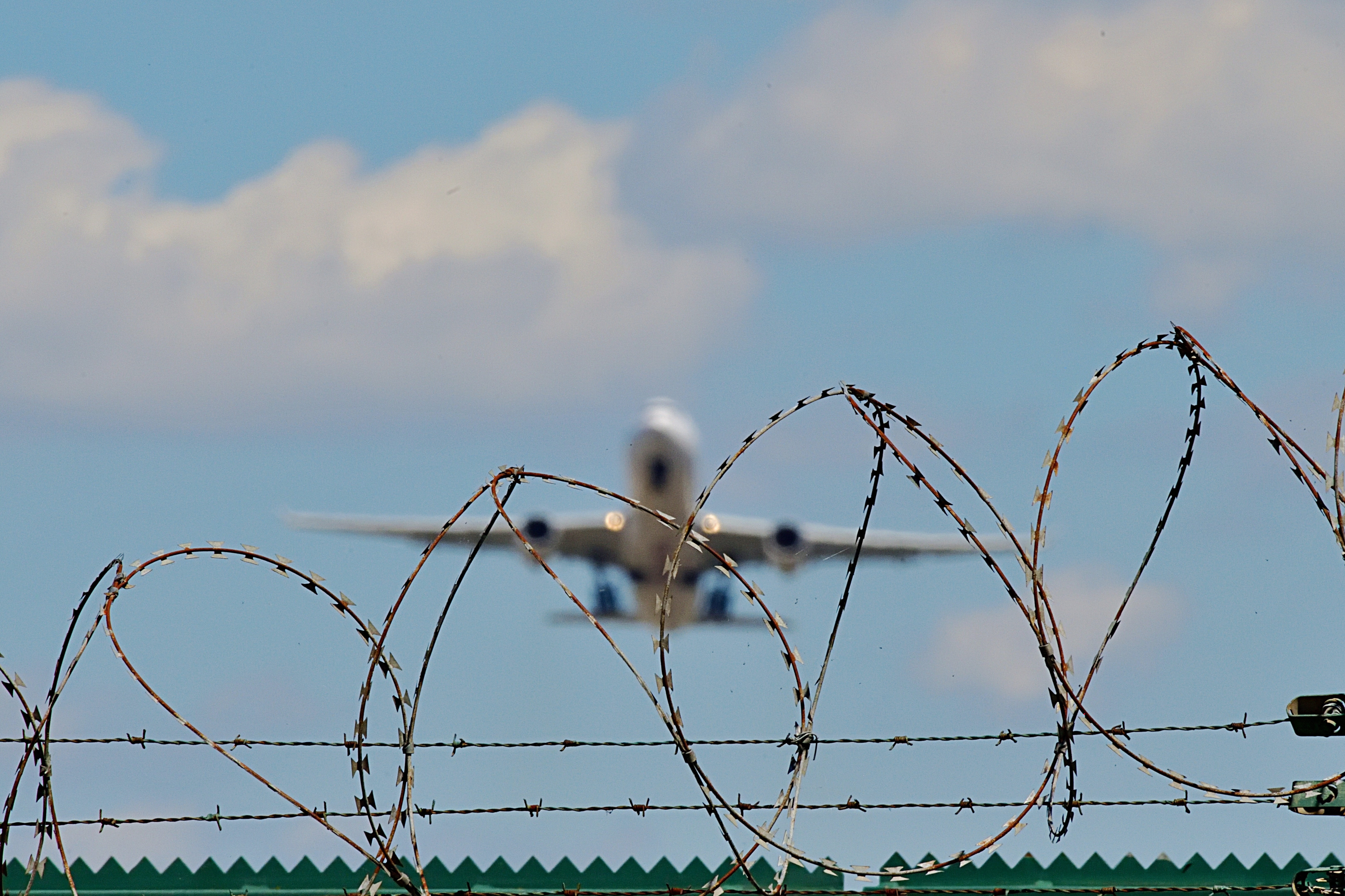 Ein Flugzeug startet von einem Flugfeld hinter Stacheldraht