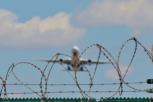 Ein Flugzeug startet von einem Flugfeld hinter Stacheldraht