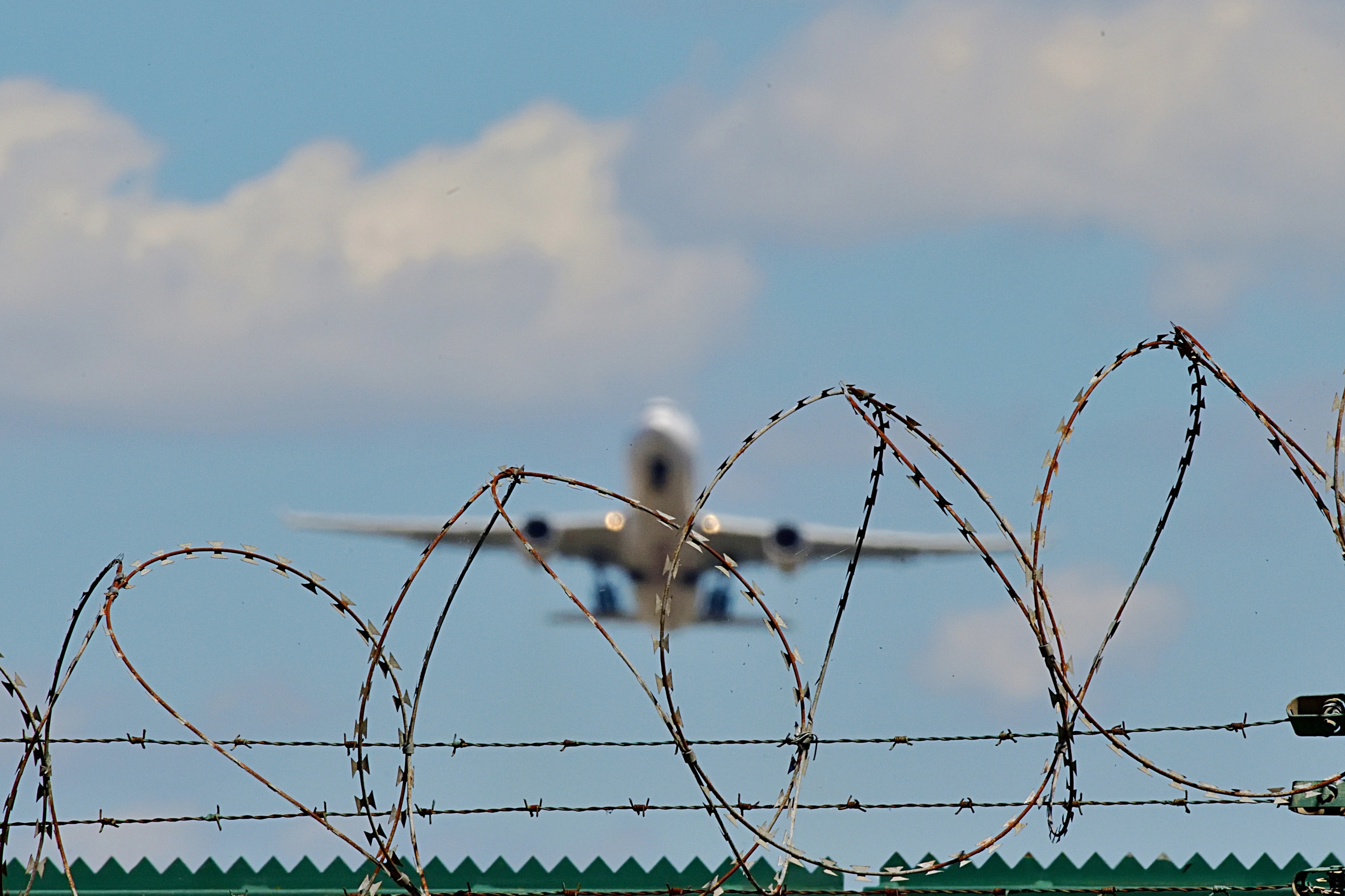 Ein Flugzeug startet von einem Flugfeld hinter Stacheldraht