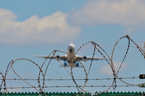 Ein Flugzeug startet von einem Flugfeld hinter Stacheldraht