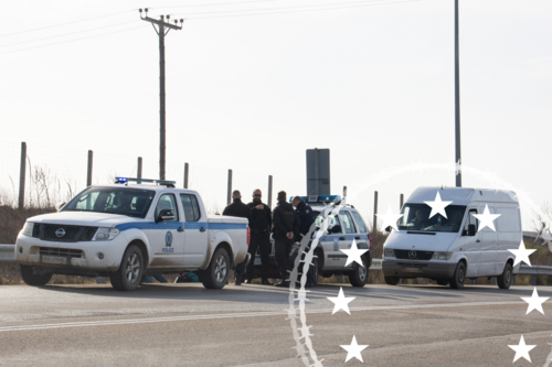 Zwei Grenzpolizeiwagen und Beamte an einer Grenze, dahinter ein weißer Transporter.