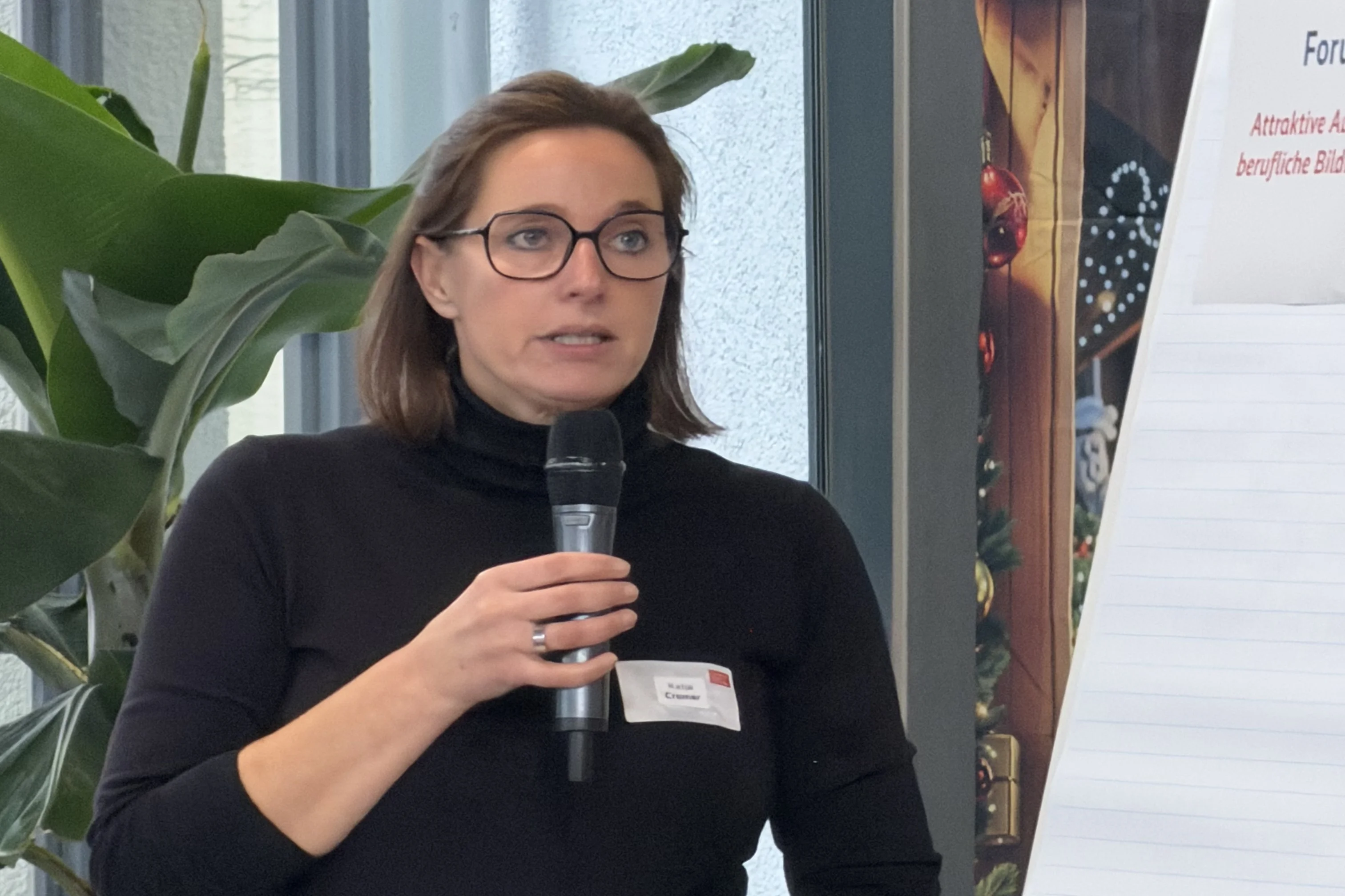 Katja Cramer mit einem Mikrofon in der Hand während sie einen Vortrag hält.