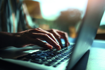 Zwei Hände tippen auf einer Laptoptastatur.