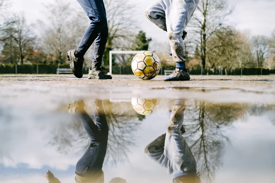 Kinder spielen Fußball auf einem Bolzplatz