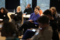 Foto von Teilnehmenden eines Workshops, die mit ihren Laptops auf dem Schoß auf Stühlen sitzen.