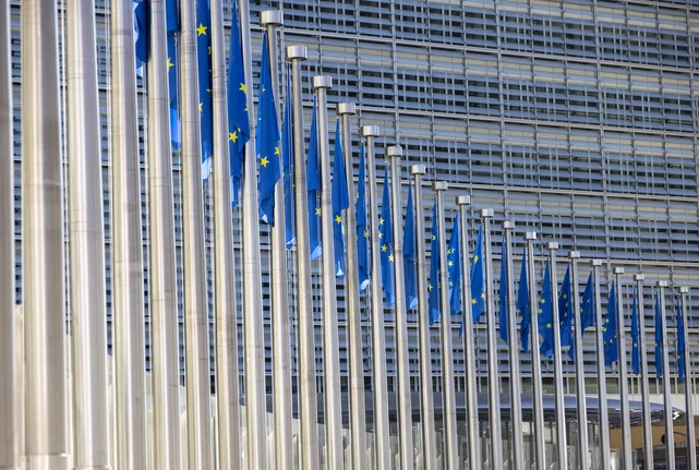 Flaggenreihe mit dem Symbol der EU vor dem Gebäude der Europäischen Kommission in Brüssel