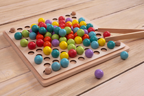 Symbolbild Innovationsmanagement: Holz-Sortierbrett mit bunten Kugeln und Pinzette – Montessori-Spielzeug zur Förderung der Feinmotorik und logischen Fähigkeiten.