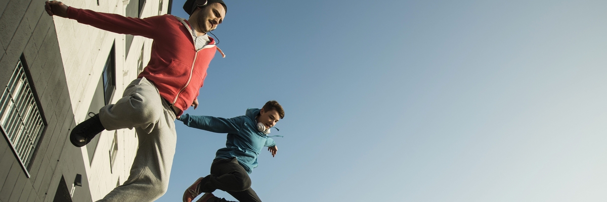2 junge Männer springen dynamisch von einer Mauer