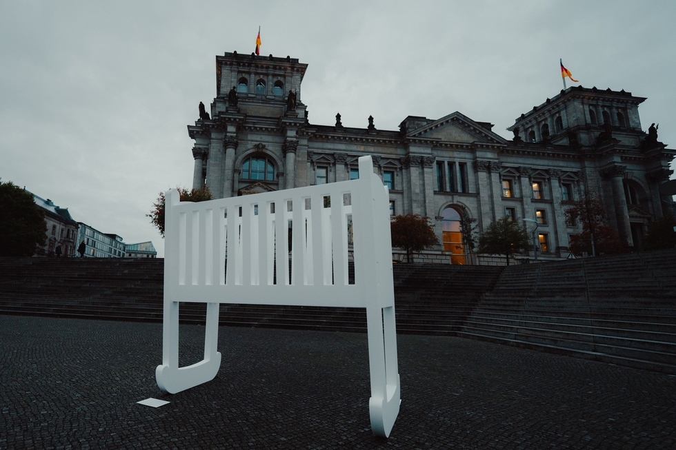 Eine leere Wiege steht vorm deutschen Bundestag.